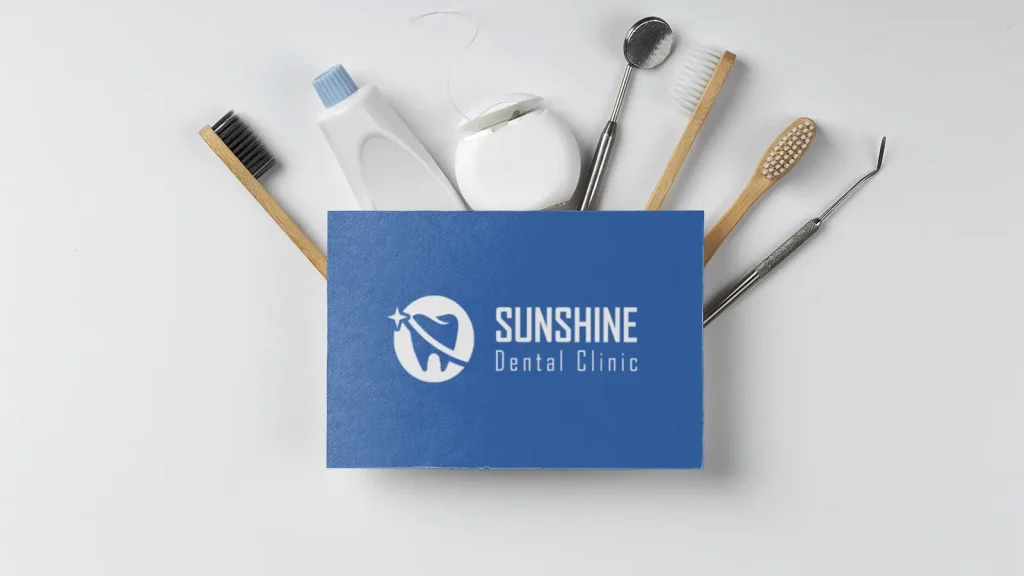 Dental Logo Design displayed on Sunshine Dental Clinic business card with dental care tools