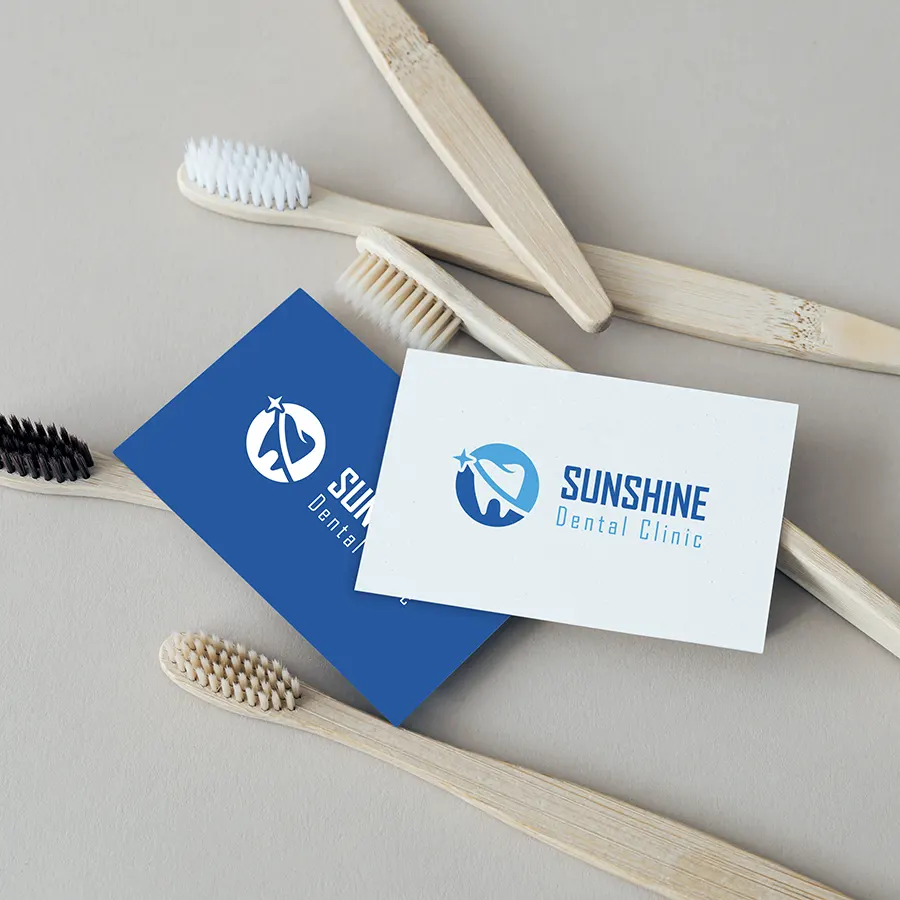 Sunshine Dental Clinic logo displayed on business cards alongside dental tools